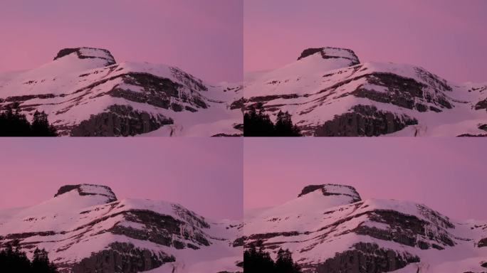 从迷人的无人机视角看，日出在白雪覆盖的山脉上。粉色的天空