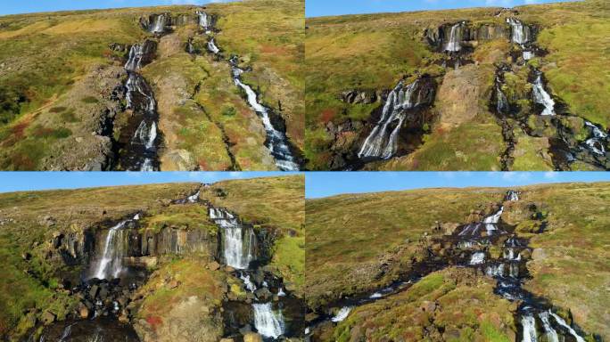 从山顶流下的水流形成许多小瀑布的令人惊叹的景色。这张照片是在一个晴朗的晴天拍摄的。山上有棕色的土壤，