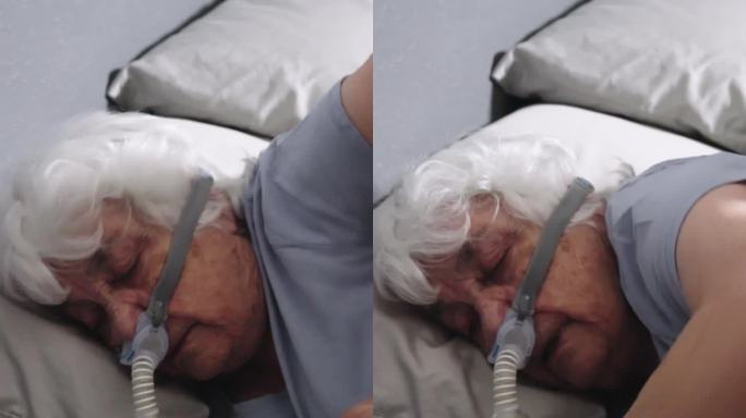 患有睡眠呼吸暂停的老年妇女睡在床上，戴着CPAP(持续气道正压通气)机来帮助她入睡