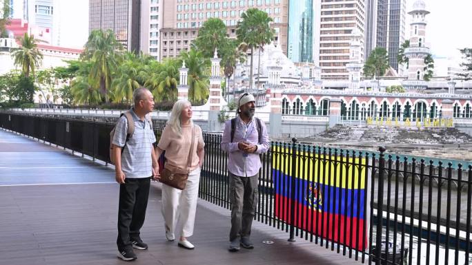 两名亚洲老年游客享受城市之旅，听当地导游讲解生命之河的建筑和历史