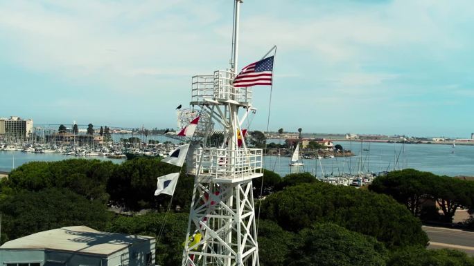 迎风飘扬的美国国旗;一座海军纪念碑，描绘了一艘俯瞰海湾的军舰，位于加利福尼亚州圣地亚哥的洛马角