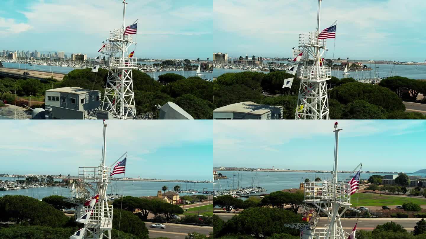 迎风飘扬的美国国旗;一座海军纪念碑，描绘了一艘俯瞰海湾的军舰，位于加利福尼亚州圣地亚哥的洛马角