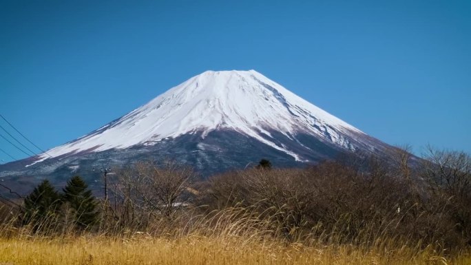 在蓝天的日子里，富士山映衬着群山和草地，是游客和旅行者的地标和目的地。大自然的美在平和中伴着缓慢的冬