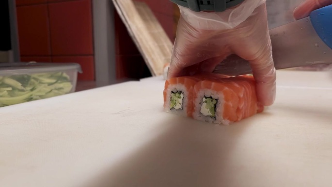 见证日本厨师熟练切片时的精准度。费城卷成8个均匀的碎片，每个切割揭示了精心制作这些美味的卷展示大师背