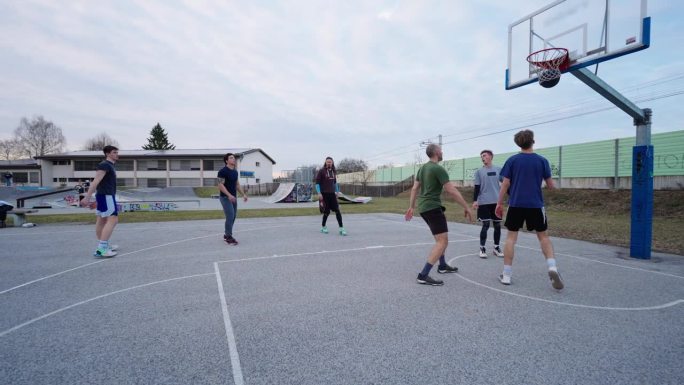 在室外球场和朋友们玩街球游戏时，快乐的年轻人在投篮