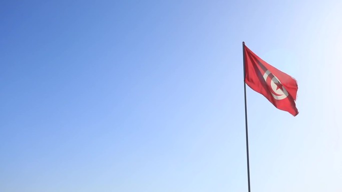 突尼斯国旗在湛蓝的天空下飘扬，强调民族自豪感