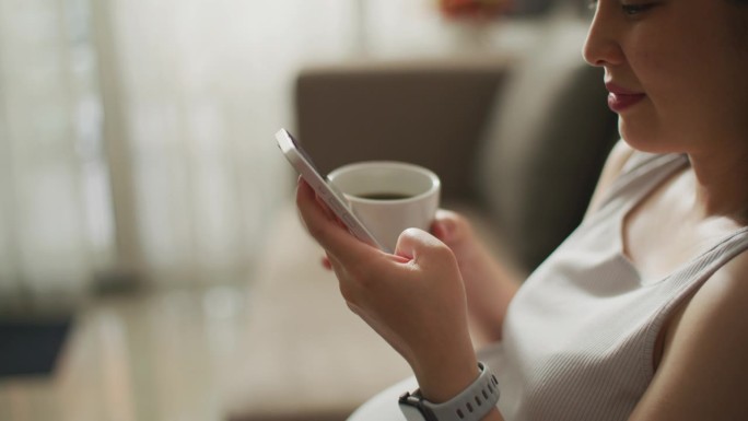 女性使用智能手机家庭休闲时刻喝咖啡玩手机