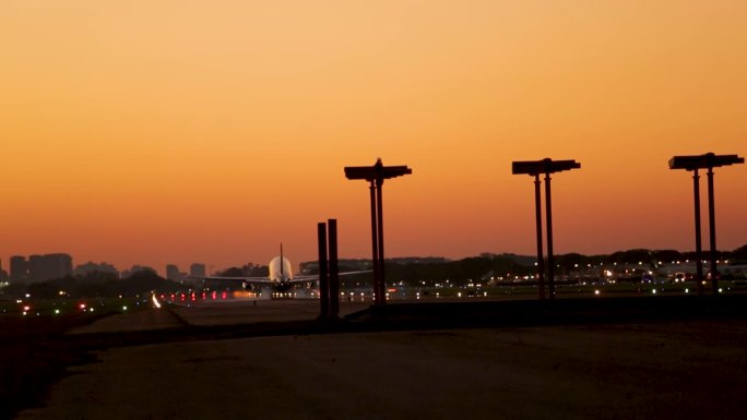 飞机降落在跑道黄昏与城市天际线剪影，金色的天空背景