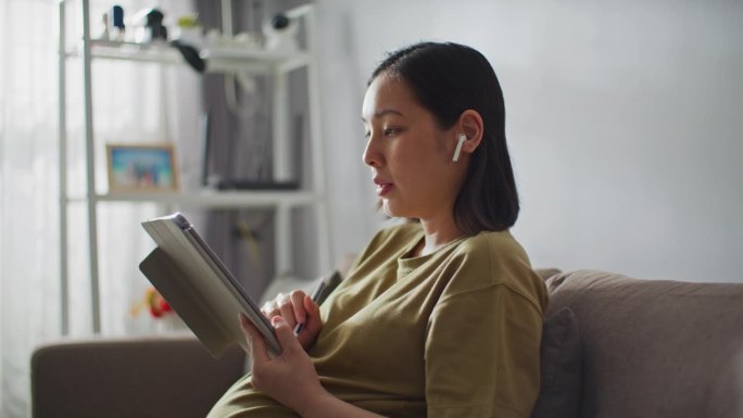 在家工作的孕妇孕妇坐在沙发指导网上讨论工