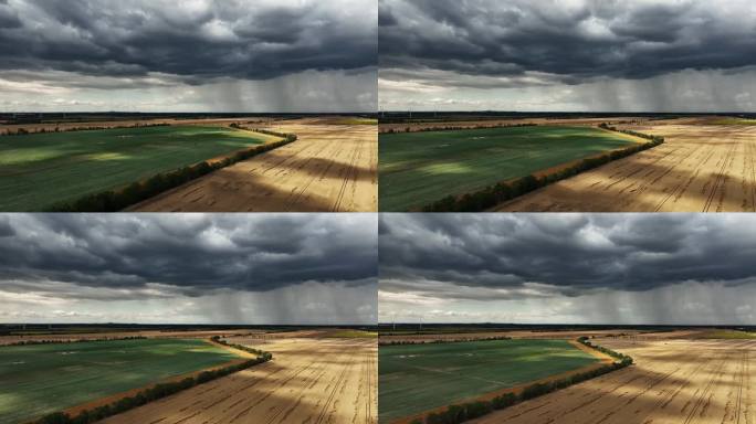 漆黑的天空和大片的雨云笼罩着田野。远处下着大雨。沿着耕地飞行。