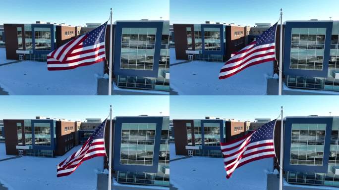 美国国旗的空中特写。学校建筑的背景与明亮的早晨的阳光。地上有雪。
