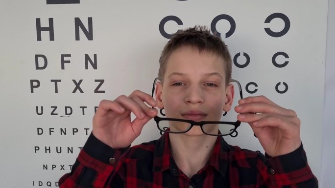 一个十几岁的男孩戴着眼镜去看眼科医生