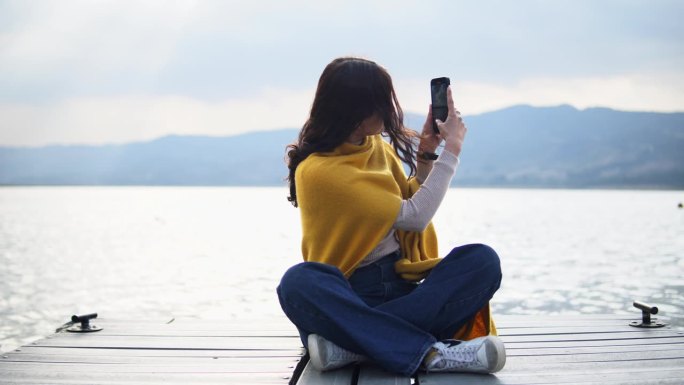 女人用智能手机捕捉湖边的回忆