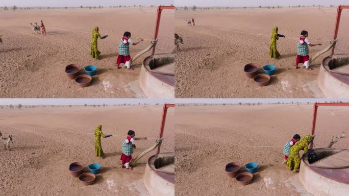 空中特写。在贫瘠的塞内加尔撒哈拉沙漠萨赫勒地区，三个黑人妇女在驴子的帮助下从一口深井里打水。干旱，气
