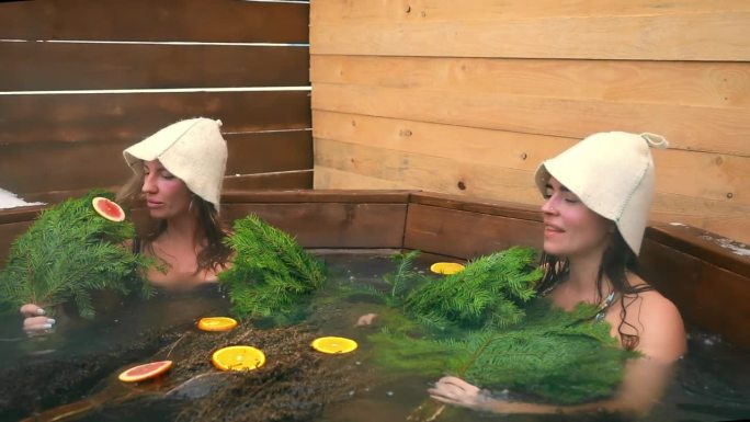 女孩们拿着扫帚和橘子在澡盆里放松