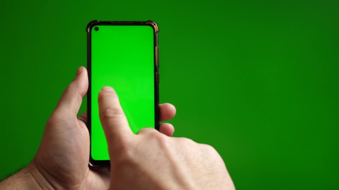 绿色屏幕的智能手机用手指按在绿色背景上。