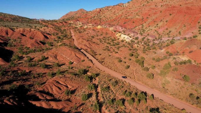 越野车行驶在弯曲的地面道路在红色沙漠与岩石鸟瞰图