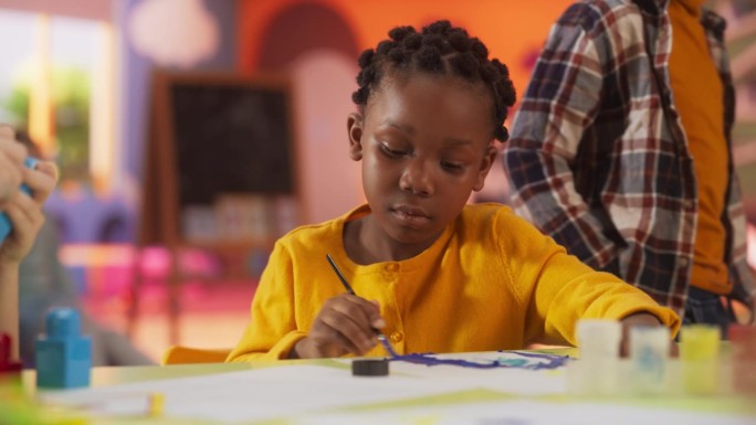 一个兴奋的非洲女孩在幼儿园用水彩画的肖像。天才黑人孩子创作艺术作品。快乐的孩子在现代日托中心学习创造