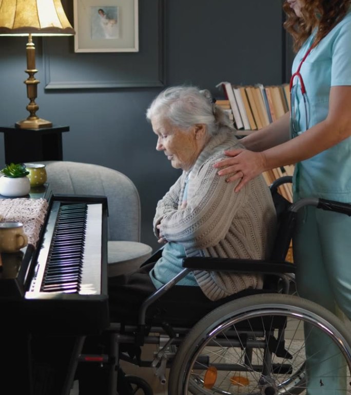 一名护理人员在空闲时间推着坐在轮椅上的老妇人弹钢琴