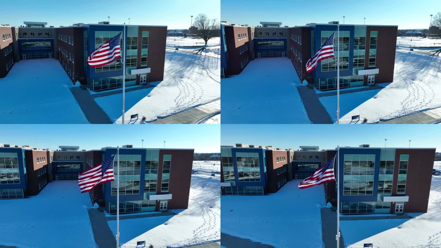 美国国旗在学校建筑旁的航拍照片。砖立面，带窗户。晨光照在雪地上。