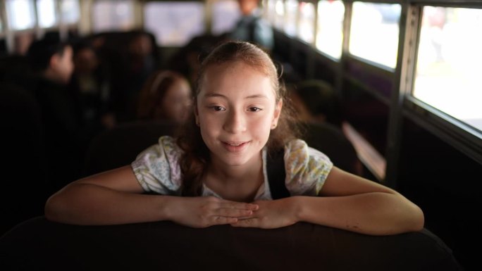 一个小女孩坐在校车上上学的肖像