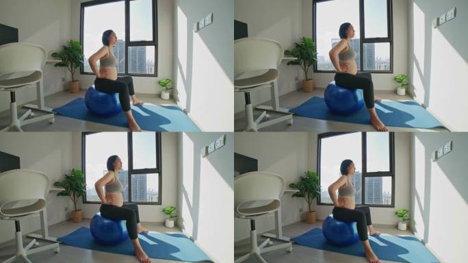 孕妇坐在家里的健身球上做骨盆底旋转