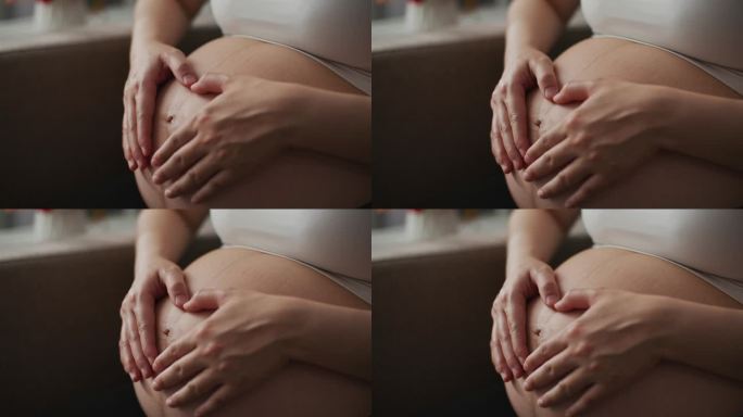 特写镜头:孕妇在赤裸的肚子上制作心形手