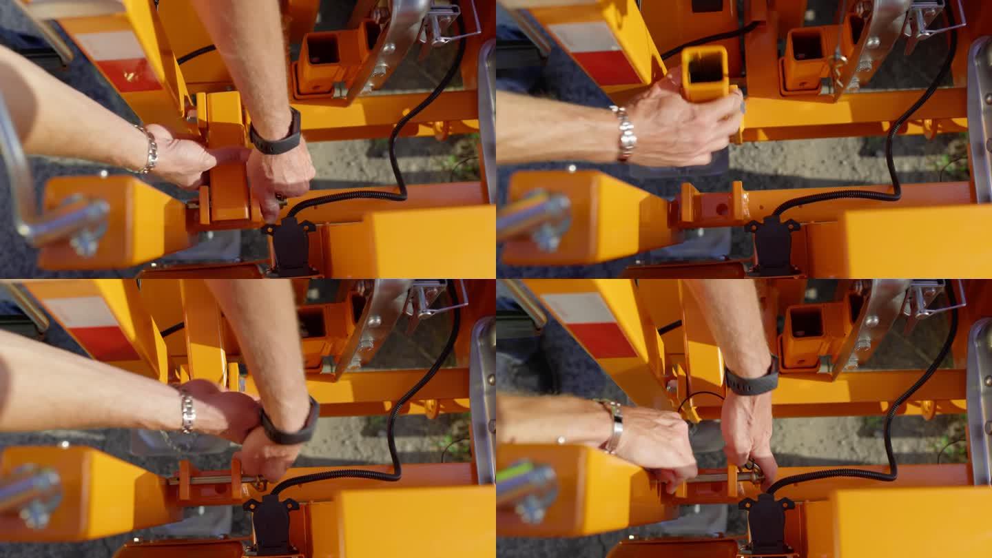 一名工人的手进入框架，从移动停车灯上的橙色小臂上取下锁定销。