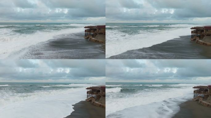 暴风雨的海浪冲击着海滩上的一座小高跷房子