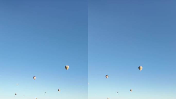 在一个阳光明媚的日子里，许多热气球在卡帕多西亚上空飞舞。