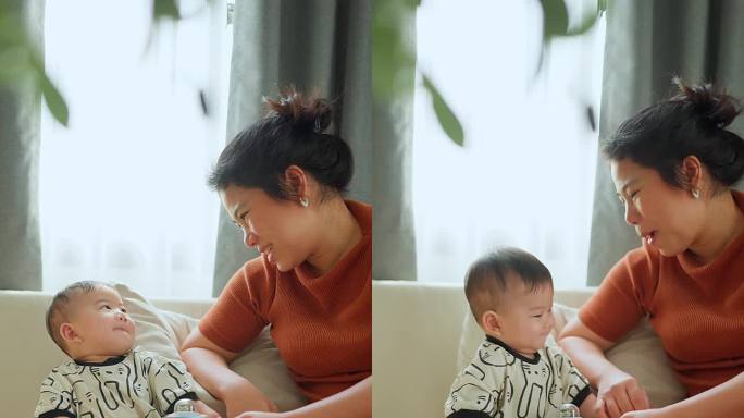 年轻可爱的妈妈给可爱的亚洲小男孩读睡前故事书，小男孩坐在奶奶的腿上，在家里读绘本家庭生活方式