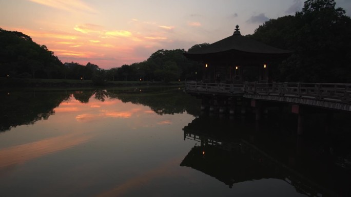 日落时分，观赏迷人的户田寺建筑群，充满活力的橙色色调反射在水面上，凸显了日本奈良小寺庙的魅力。