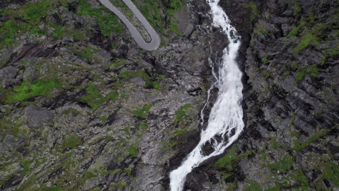 特罗尔福森瀑布从悬崖上倾泻而下，流入挪威的特韦雷瓦河。瀑布旁边可以看到蜿蜒曲折的特罗尔斯蒂根山路的急