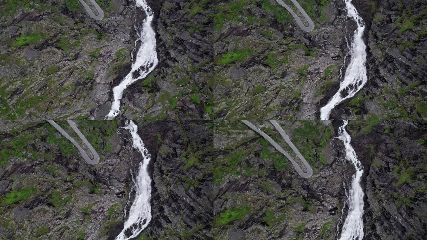 特罗尔福森瀑布从悬崖上倾泻而下，流入挪威的特韦雷瓦河。瀑布旁边可以看到蜿蜒曲折的特罗尔斯蒂根山路的急