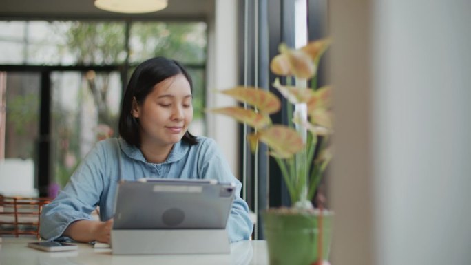 在咖啡店用笔记本电脑工作的亚洲女性