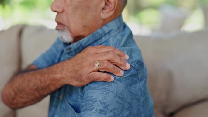 肩膀疼痛，压力和老人的手在沙发上与肌肉，问题或关节炎危机在家里。患有纤维肌痛、痉挛或骨质疏松症的老年