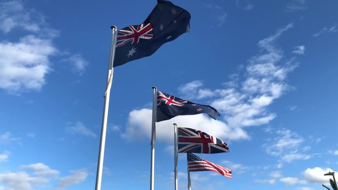澳大利亚、新西兰、英国、美国等西方盟国的国旗在蔚蓝的天空下迎风飘扬。