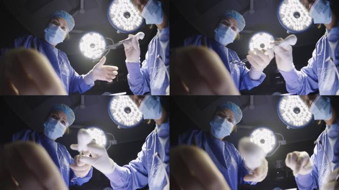 低广角视角外科医生的手与护士和手术灯一起工作，医生将棉签放在镜头上