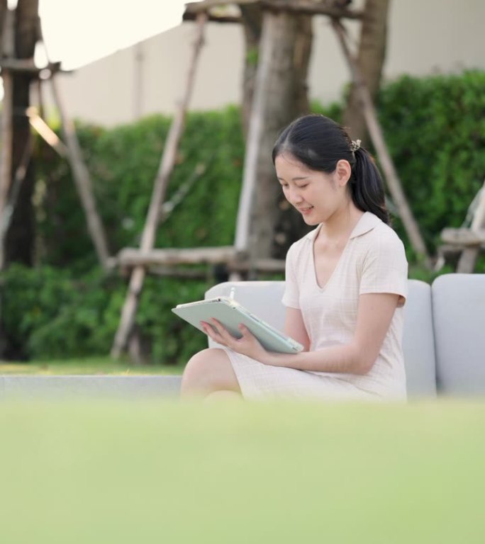GenZ亚洲女性兴高采烈地坐在笔记本电脑前阅读有关她的股票投资新闻，在她的花园里投资
