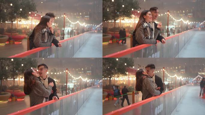 浪漫的年轻情侣在圣诞夜的溜冰场外接吻