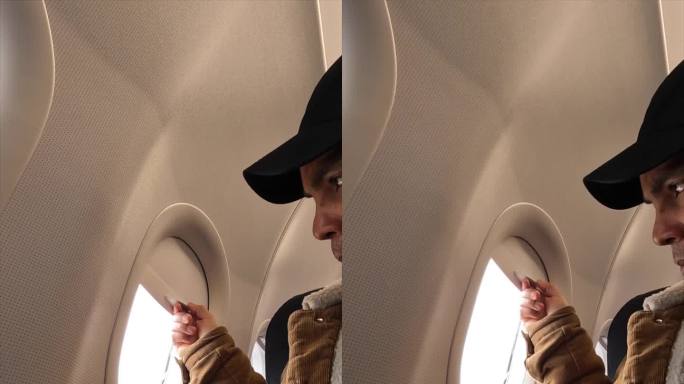 乘客在飞行途中用手打开飞机窗户