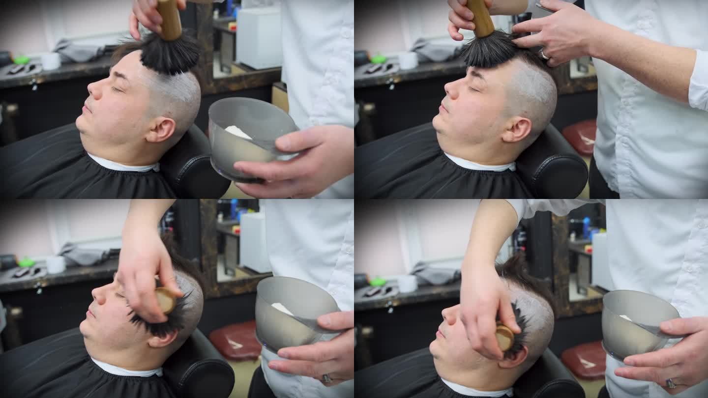 理发师在用直刀剃须之前，先用刷子在顾客头上涂上泡沫