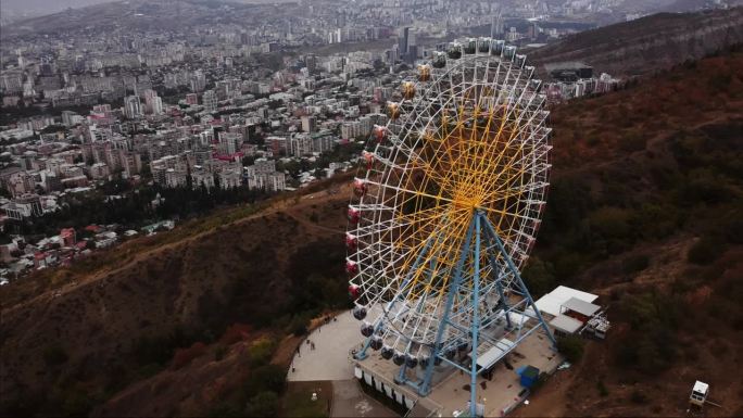 摩天轮在第比利斯建在山上的公园里旋转的航拍时间