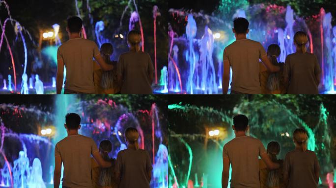 一家人欣赏着灯火通明的舞蹈喷泉