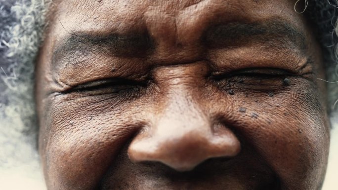 一个平静的皱纹南美黑人妇女闭上眼睛冥想的微距特写，睁开眼睛盯着镜头，细节80多岁老人的脸