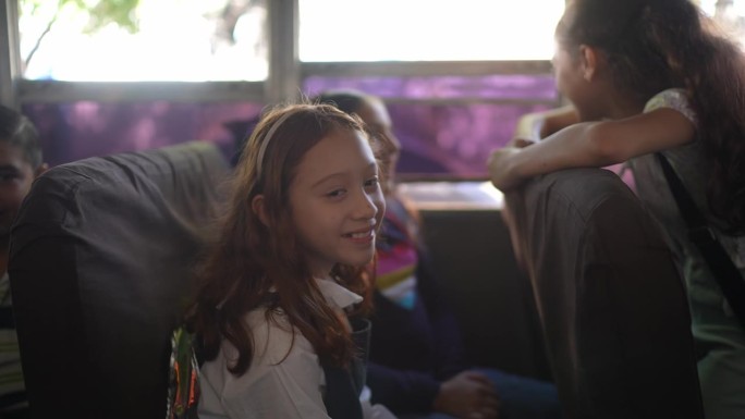 一个小女孩在校车上上学时与朋友交谈的肖像