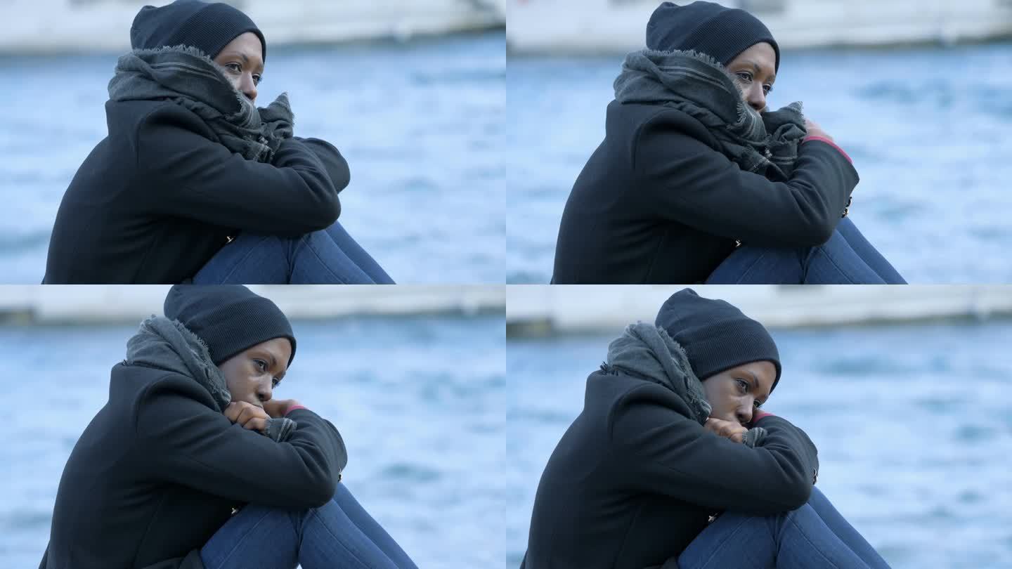 年轻忧郁的黑人女子在寒冷的日子里坐在码头上忧郁得像湖水
