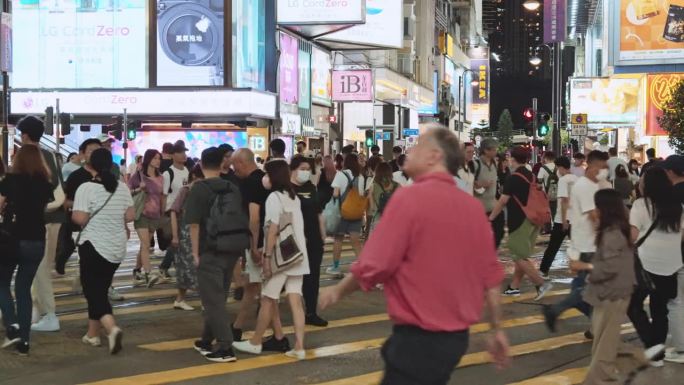 在香港铜锣湾购物区，拥挤的亚洲华人，游客走过斑马线。交通运输，公共交通，亚洲旅游旅游，城市夜生活概念