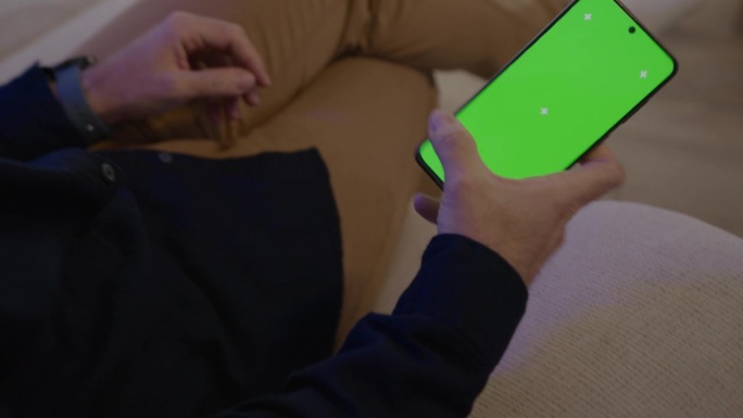 男性手拿手机的细节，绿色色度屏，便于图文插入