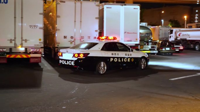 日本警察上了车。日本警车头灯亮着。